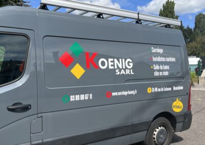 Marquage publicitaire sur un utilitaire Renault – Logo et coordonnées visibles sur la route